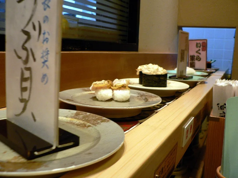 Plates of sushi moving along a conveyor belt at a kaitenzushi restaurant in Kyoto