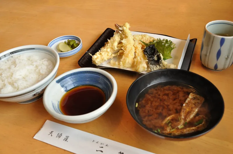 A tempura set meal with rice, miso soup, dipping sauce and a plate of shrimp and vegetable tempura