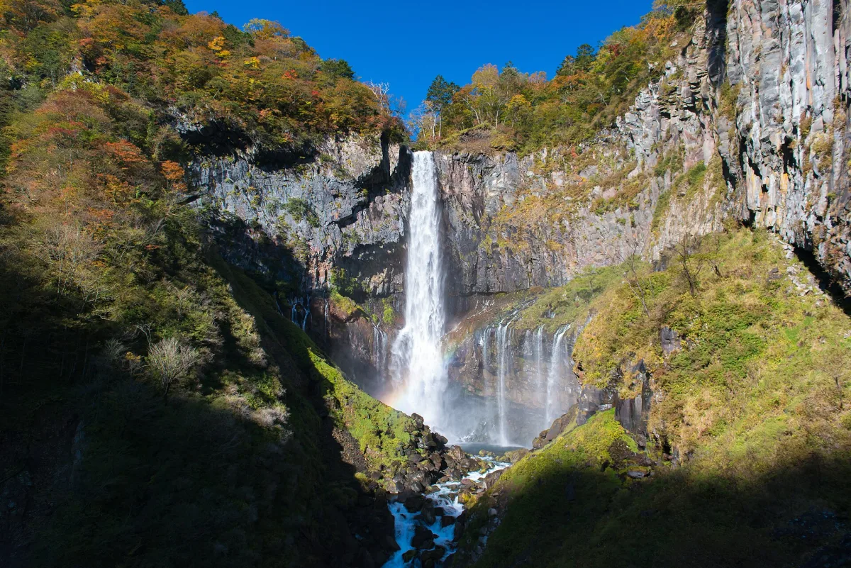 Kegon Falls dropping down a cliff among autumn trees in Nikko