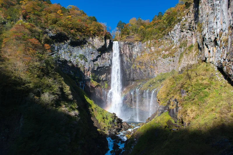 Kegon Falls dropping down a cliff among autumn trees in Nikko