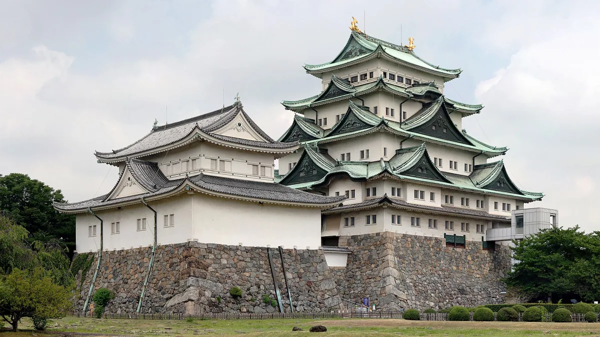 Nagoya Castle's main keep with green roofs and golden ornaments on a stone base