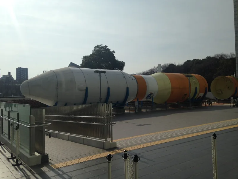 Full-size H-IIB rocket body displayed outdoors in front of Nagoya City Science Museum