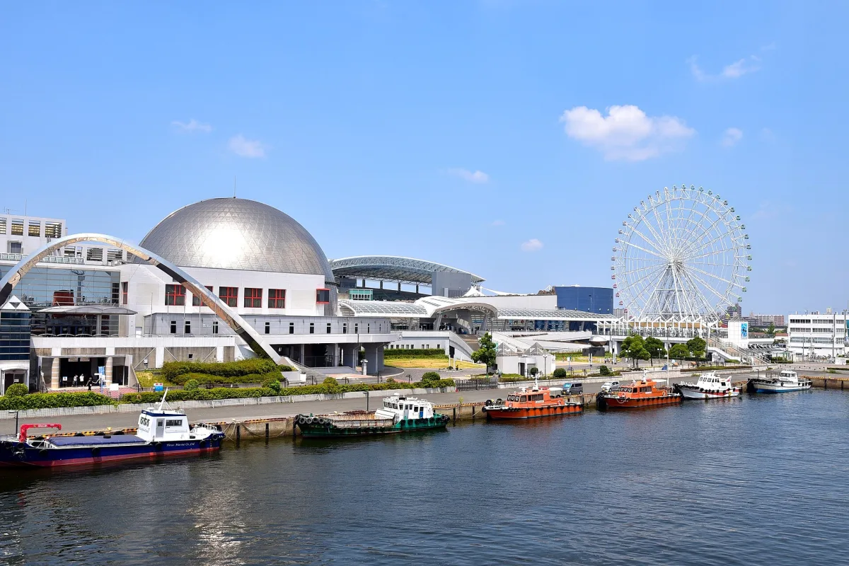 The Port of Nagoya Public Aquarium's domed building beside the harbor, with a Ferris wheel behind