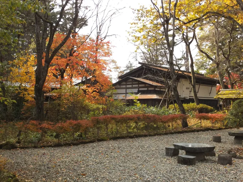 Garden of the Aoyagi samurai house with autumn trees and a traditional building