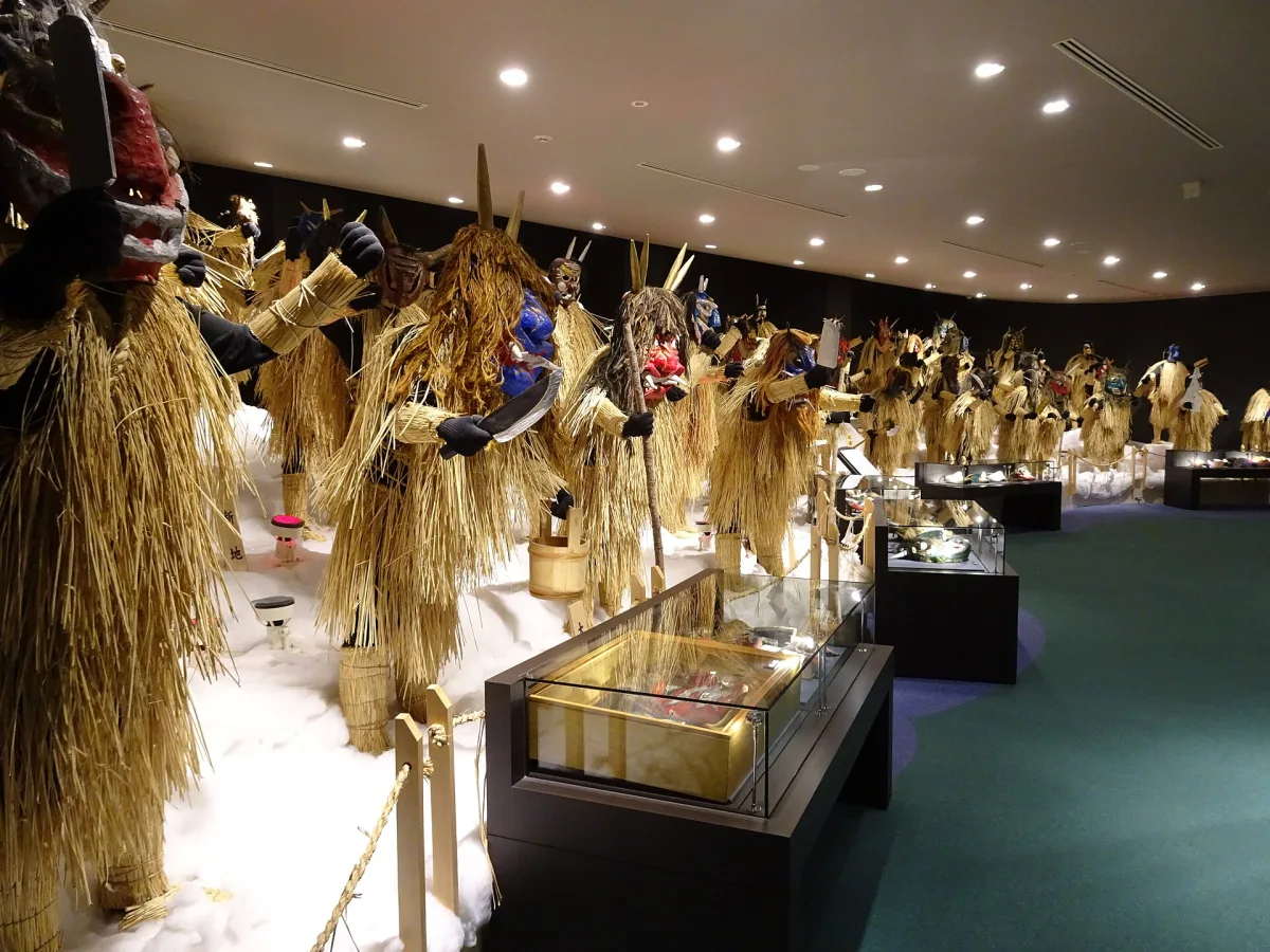 Rows of straw-clad Namahage figures with different masks on display inside the Namahage Museum