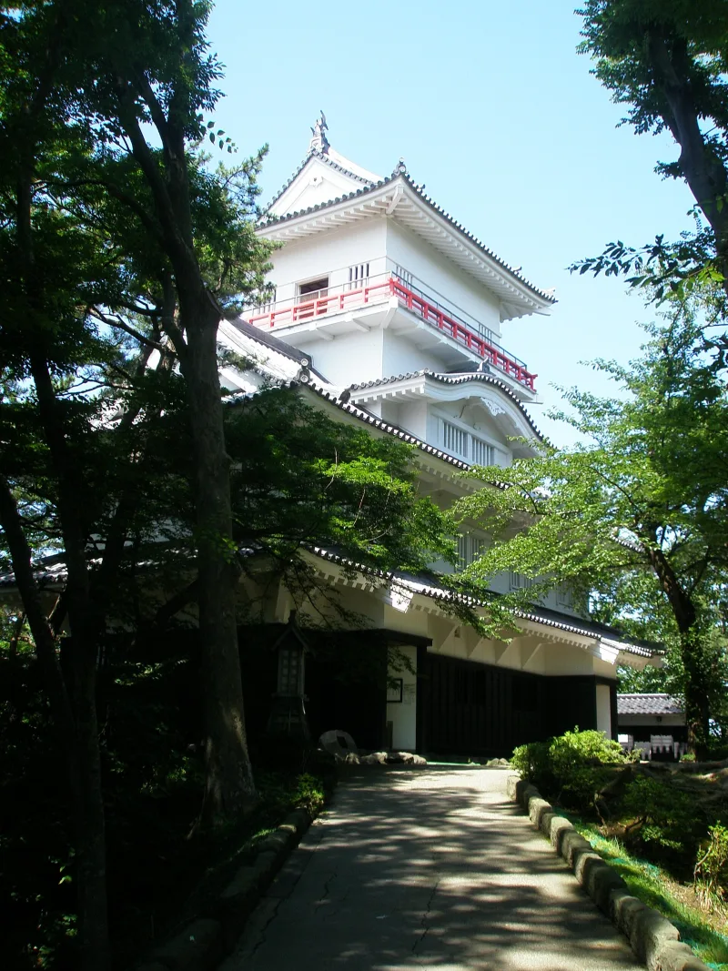 The white reconstructed Osumi-yagura corner turret of Kubota Castle among pine trees