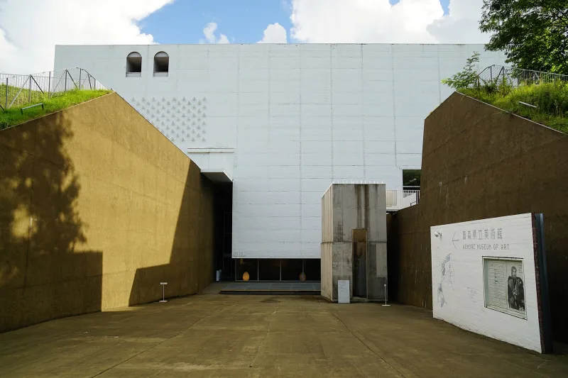 Sunken entrance court of the museum, with earth-coloured walls cut into the ground below the white building