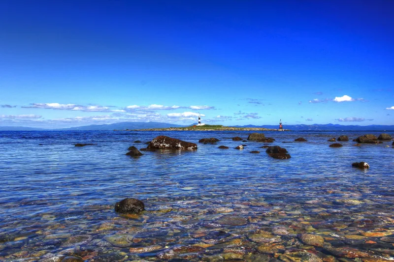 Clear, rocky shallows off Cape Oma with Benten Island's lighthouse on the horizon