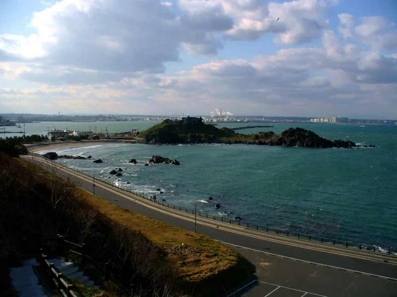 Kabushima, a small green island joined to the shore, seen from the coastal road above the sea