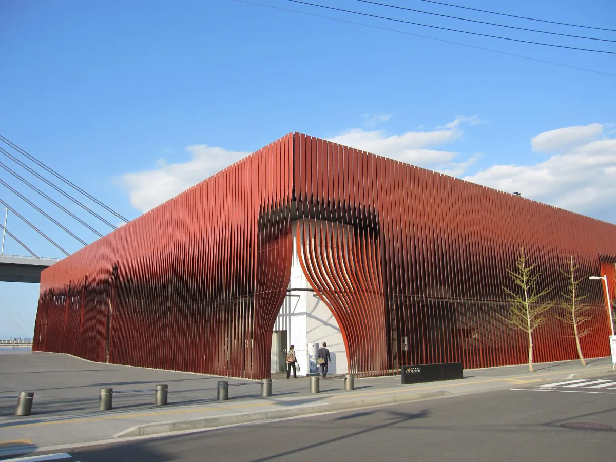 Red ribbon-like steel exterior of the Nebuta Museum Wa Rasse by Aomori Bay