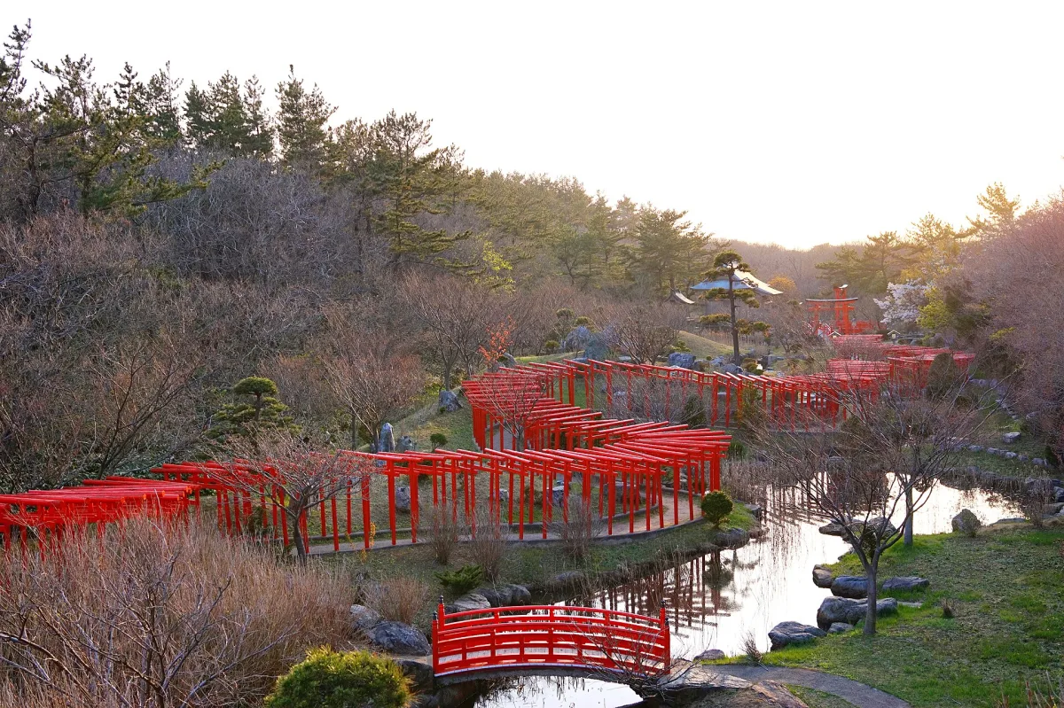 Red torii gates winding around a pond in the garden of Takayama Inari Shrine