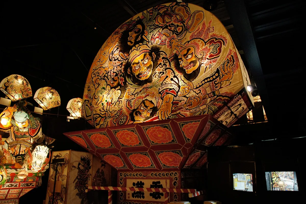 Large fan-shaped neputa lantern painted with warriors, lit up inside the exhibition hall