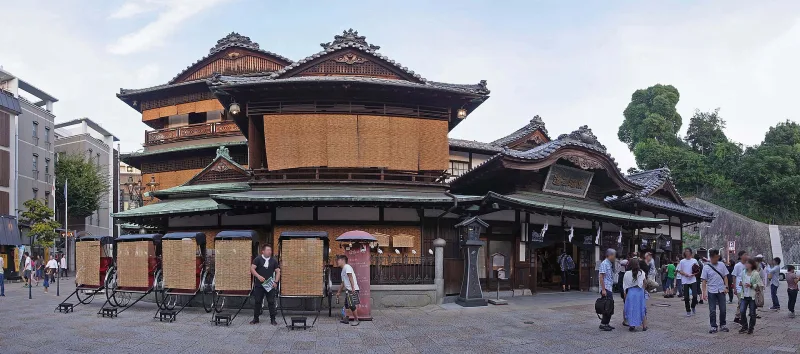 Side view of the multi-roofed Dogo Onsen Honkan building with the small tower on top