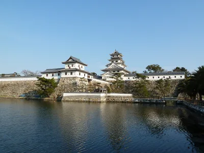 Imabari Castle keep and white turrets on stone walls above the wide seawater moat