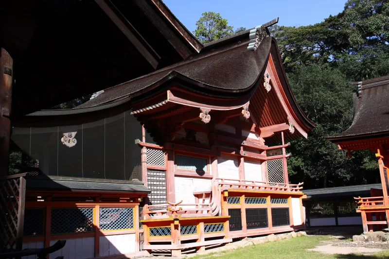 Main hall of Oyamazumi Shrine with red and white woodwork among trees