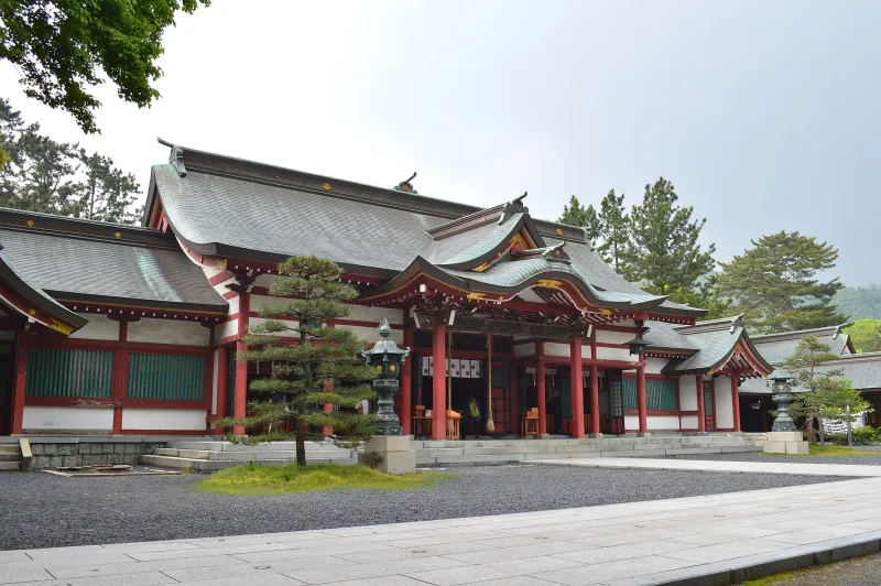Vermilion and white shrine buildings of Kehi Jingu around a gravel courtyard