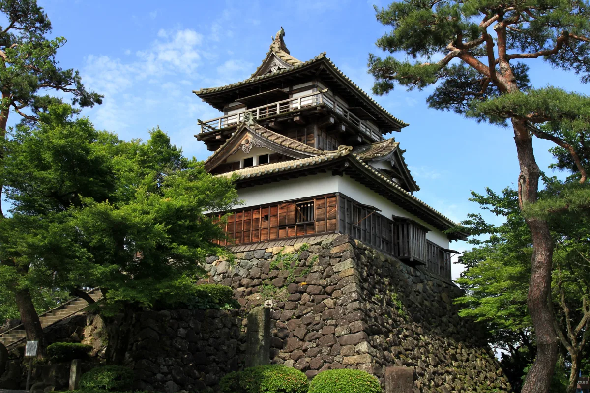The small three-storey keep of Maruoka Castle on its stone base, framed by pine trees