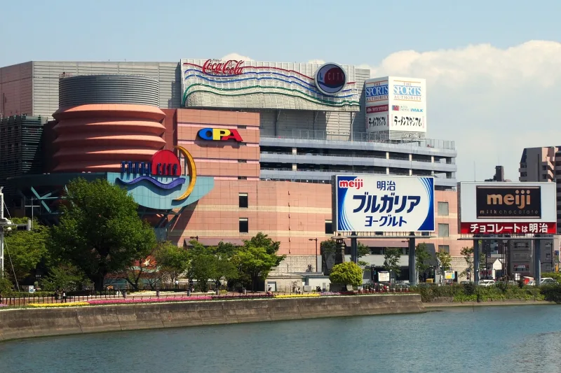 The colorful curved buildings of Canal City Hakata seen across a river