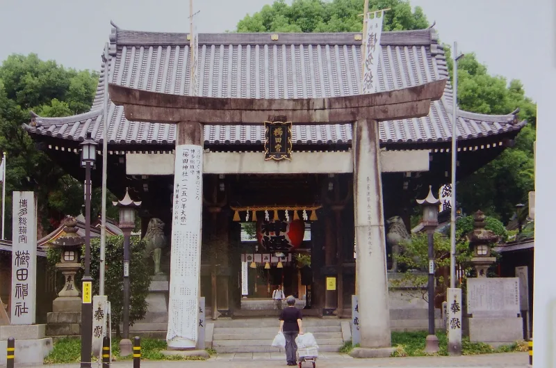 Stone torii gate and the tiled main gate of Kushida Shrine