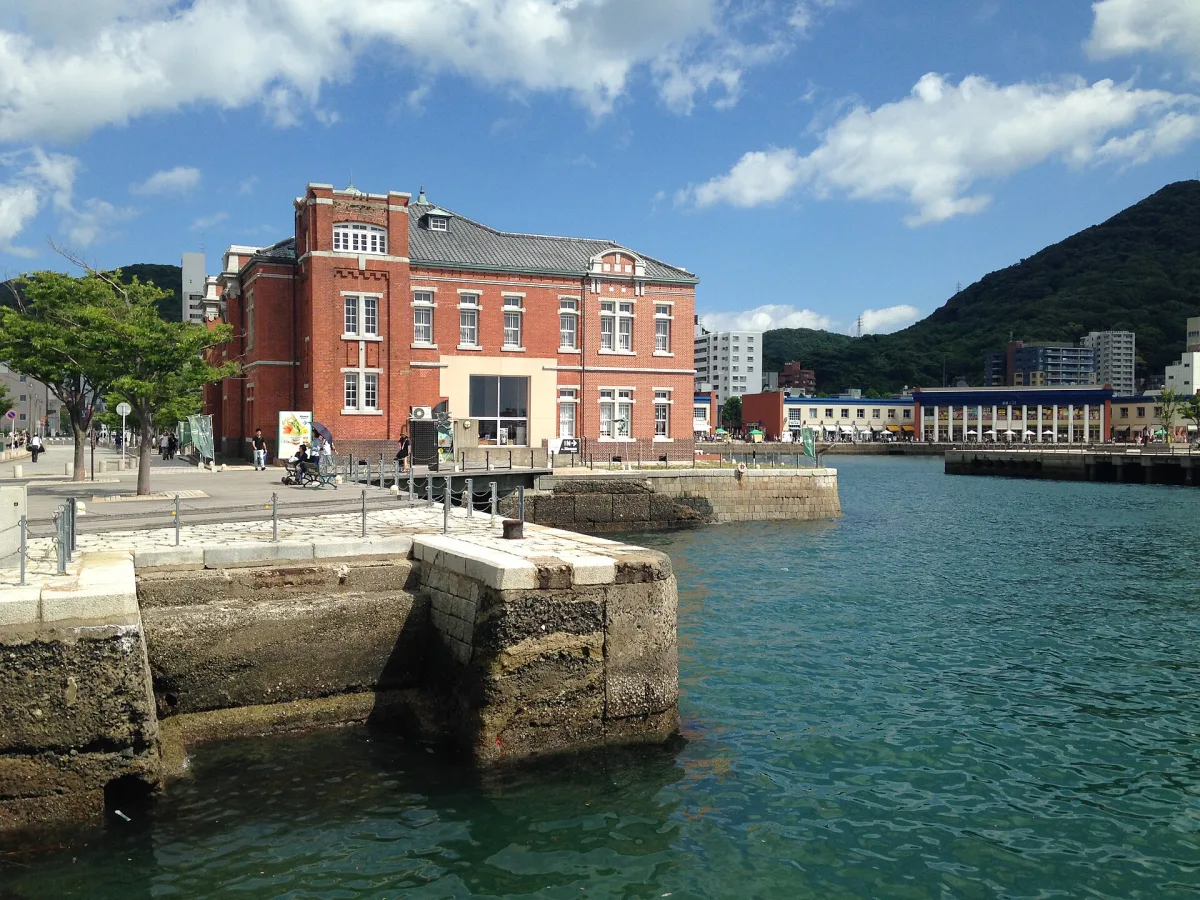 Red-brick Former Moji Customs building on the waterfront of Mojiko Retro, green hills behind