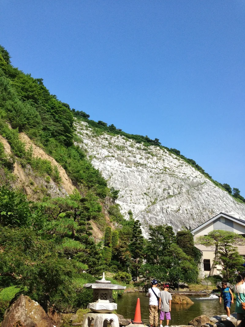 The white limestone quarry wall rising above the garden near the Abukuma Cave entrance