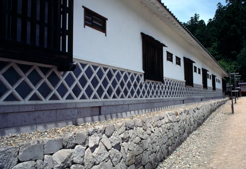 White plaster wall with a lattice pattern over a stone base at the Aizu samurai residence