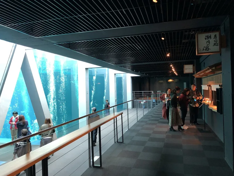 Indoor walkway beside a tall blue tank inside Aquamarine Fukushima