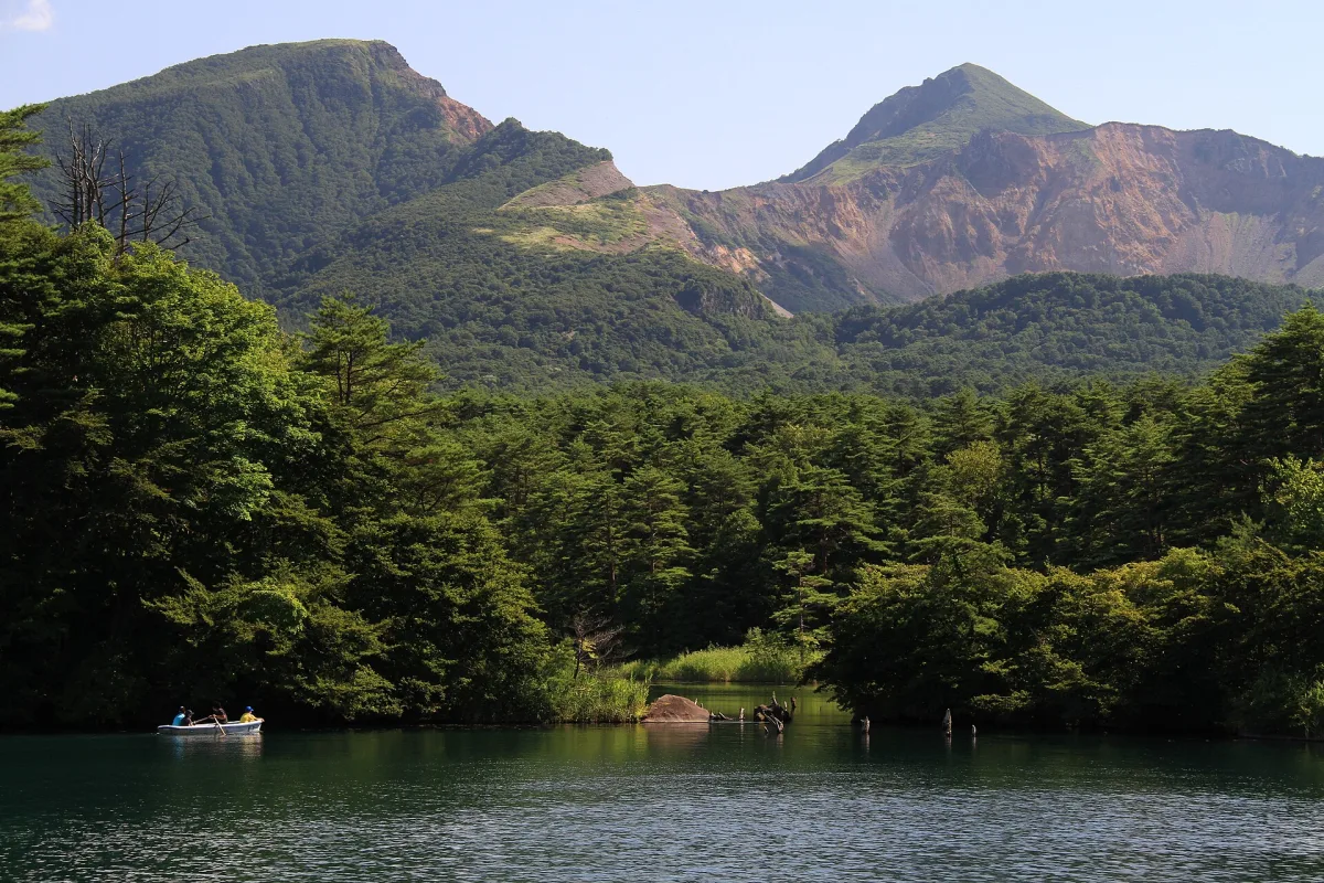 Bishamon-numa pond with a rowing boat below the craggy peaks of Mount Bandai