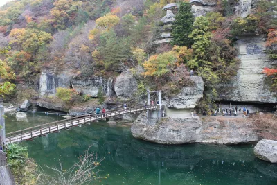Tower-like cliffs of To-no-Hetsuri with autumn leaves and a suspension bridge over green water