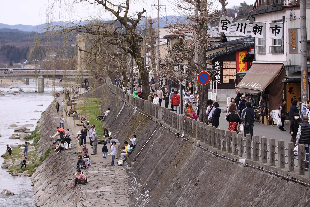 Visitors walking along the Miyagawa River past the morning market stalls in Takayama