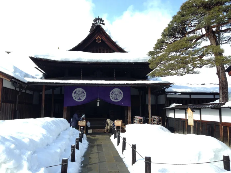 Entrance hall of Takayama Jinya with purple crest curtains and snow piled along the path