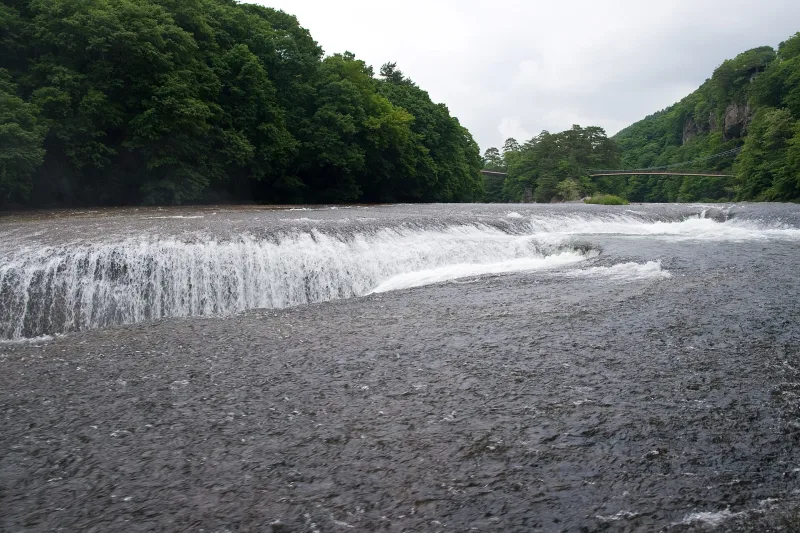 Fukiware Falls cascading into the crack in the riverbed with cliffs behind