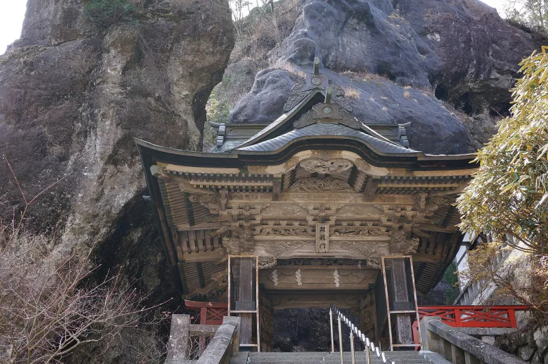 Carved wooden Soryumon gate at Haruna Shrine set below towering rocks