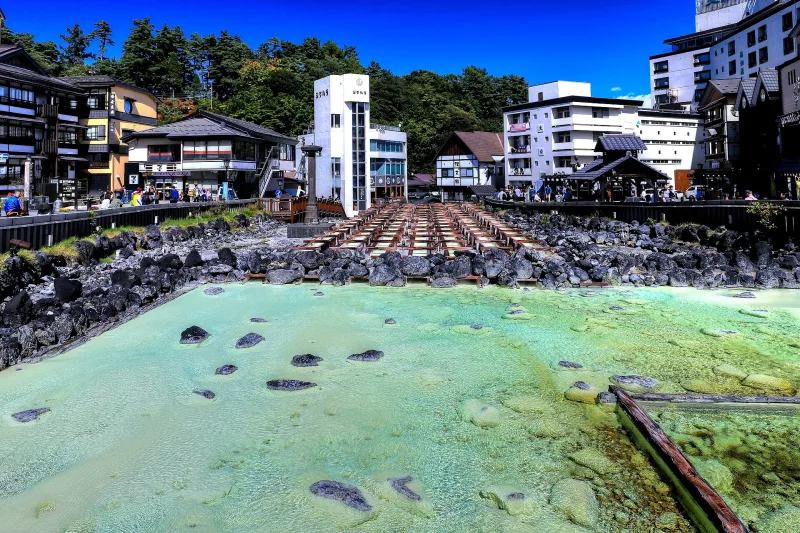 Pale green hot spring water flowing over the rocks of Yubatake in the center of Kusatsu town