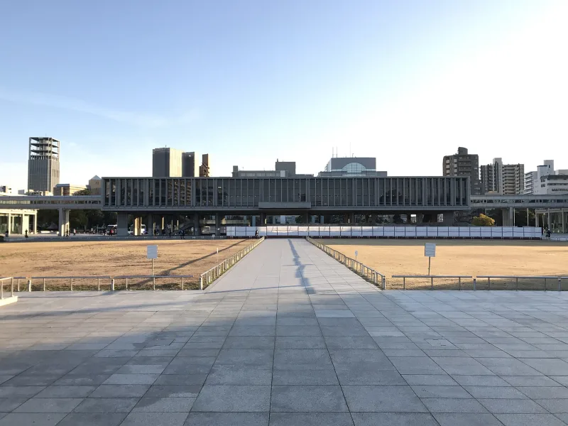 The long, raised main building of the Hiroshima Peace Memorial Museum seen across the open plaza