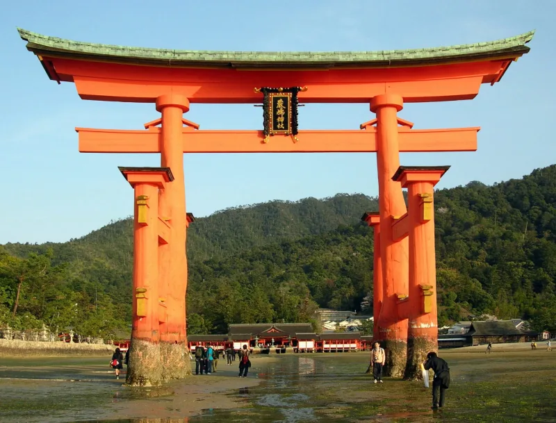 Visitors walking on the tidal flat to the great torii of Itsukushima Shrine at low tide
