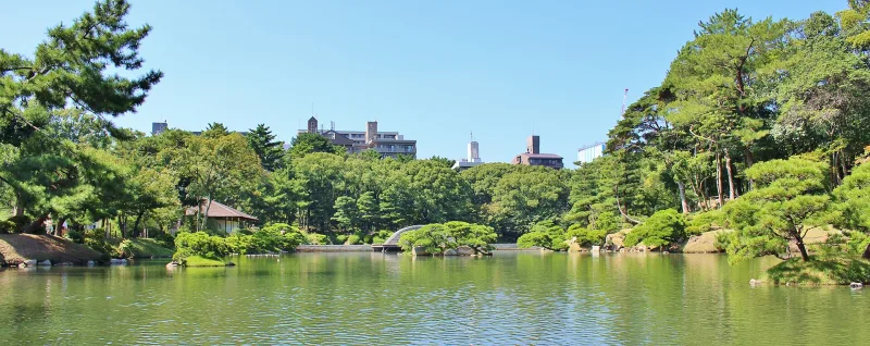 Wide view of Takuei Pond surrounded by pine trees and garden pavilions