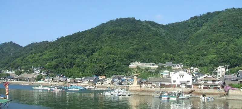 Tomonoura harbour with fishing boats, the stone lantern lighthouse and green hills behind