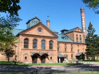 Red-brick Sapporo Beer Museum building with its tall chimney under a blue sky