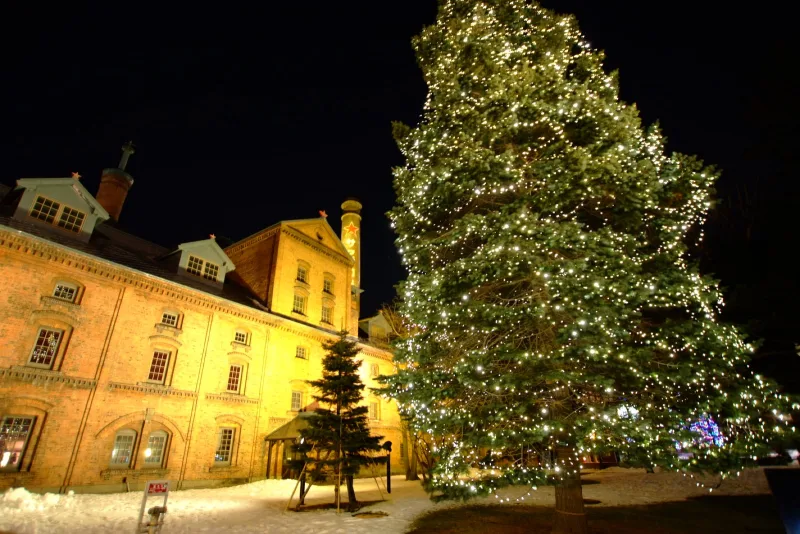 The red-brick beer museum and a lit Christmas tree on a snowy winter night