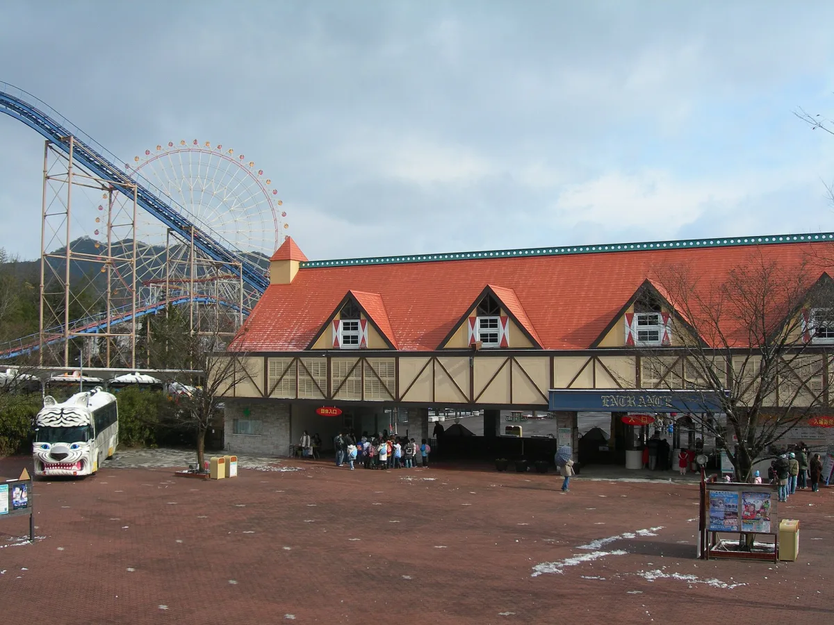 Entrance building of Himeji Central Park with a roller coaster and Ferris wheel behind