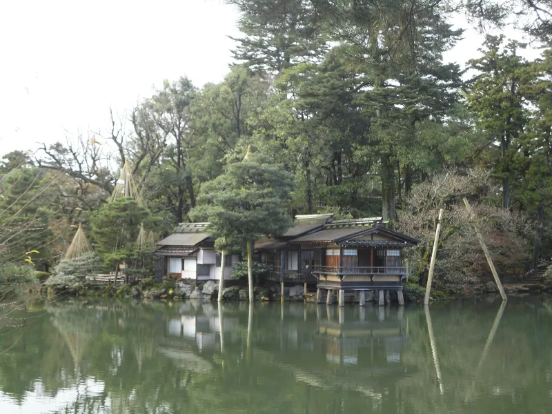 Uchihashi-tei teahouse standing over the calm water of Kasumigaike Pond at Kenroku-en