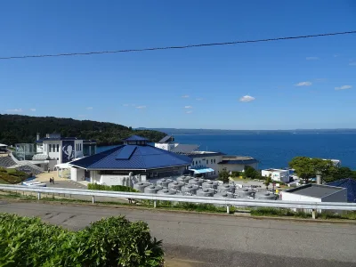 Notojima Aquarium's blue-roofed buildings on the shore of Nanao Bay under a clear sky