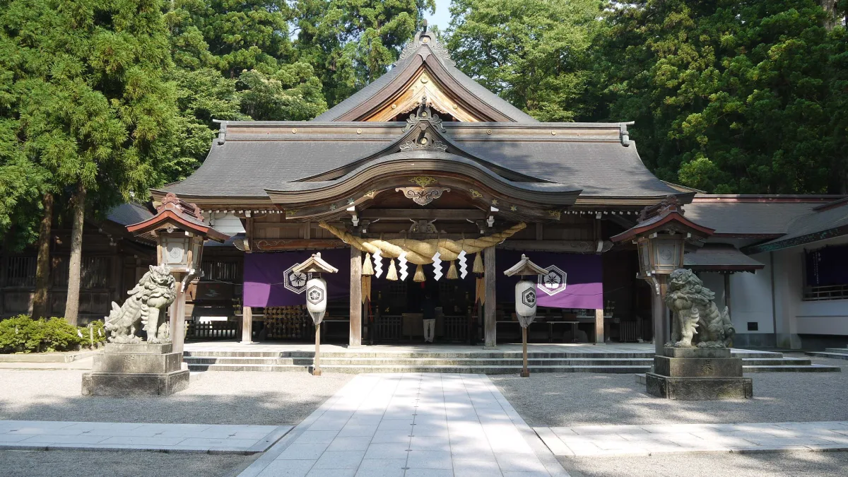Main hall of Shirayama Hime Shrine with stone guardian lions, surrounded by tall cedars