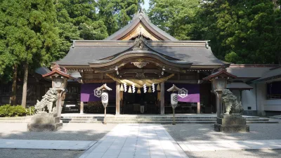 Main hall of Shirayama Hime Shrine with stone guardian lions, surrounded by tall cedars