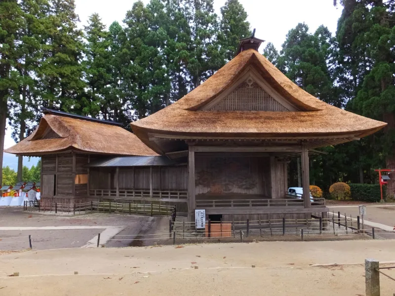 Thatched-roof Noh stage at Hakusan Shrine in the Chuson-ji precincts, backed by tall cedars