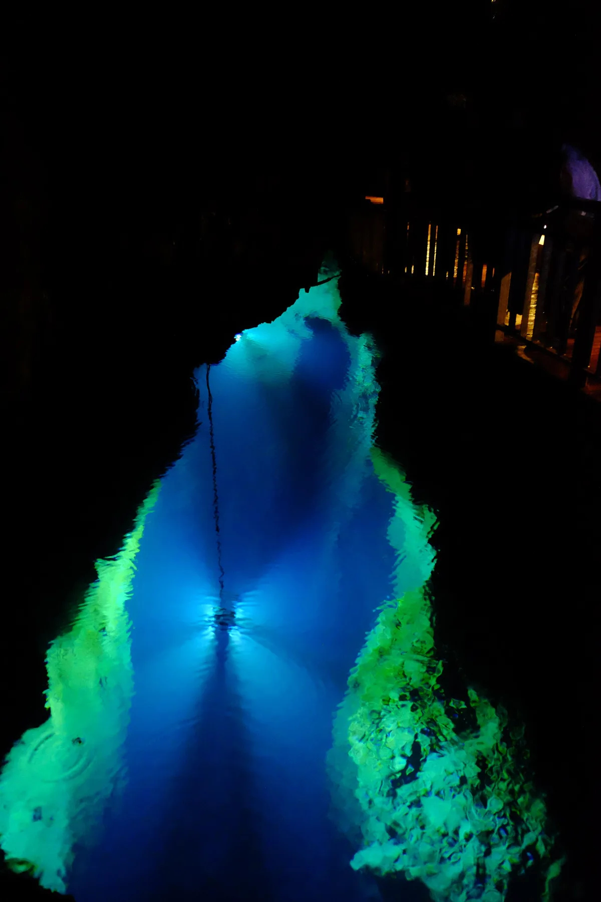 Clear, bright blue underground lake lit from below inside Ryusendo Cave