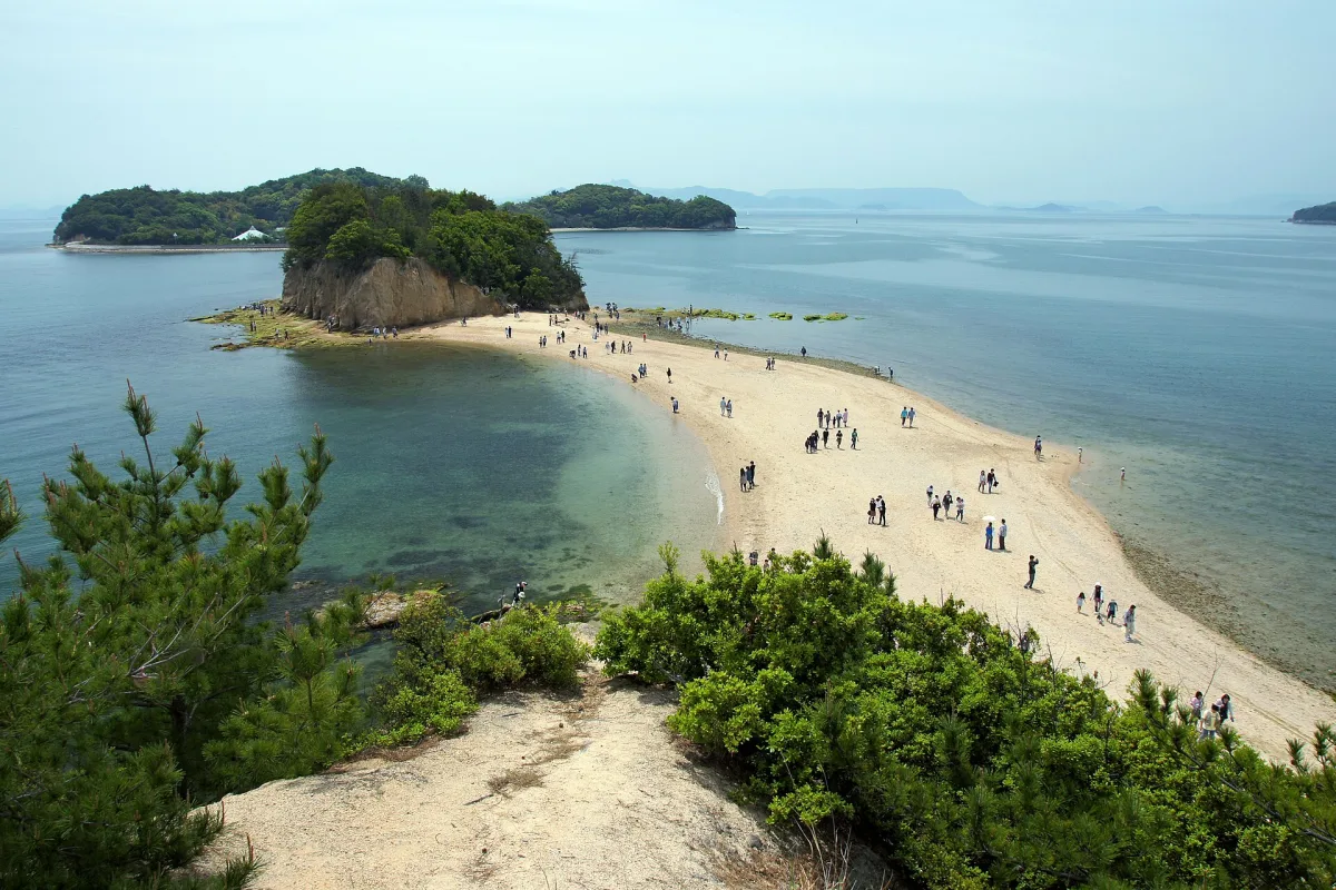 Sandbar of Angel Road stretching across calm sea to a small wooded islet at low tide