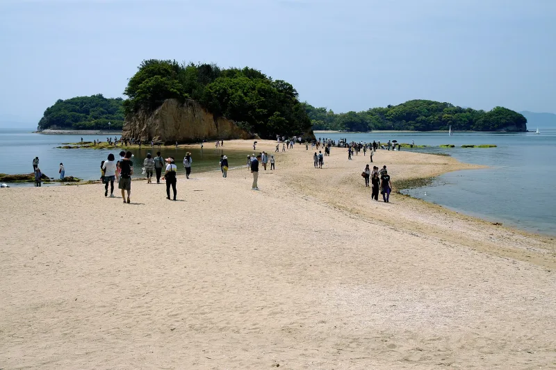 Visitors walking along the Angel Road sandbar toward a rocky islet