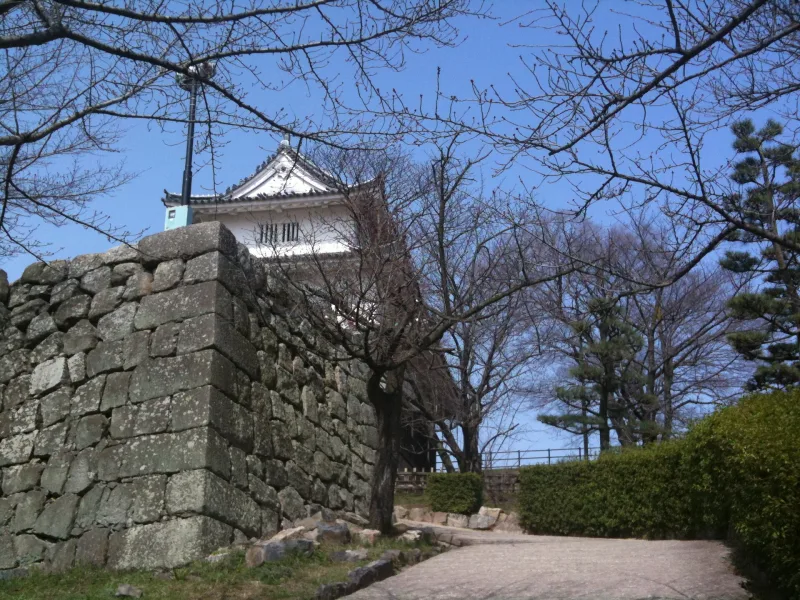 The small white keep of Marugame Castle above a stone wall